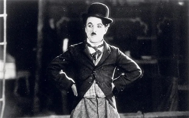 Charlie Chaplin com traje de Carlitos em cena clássica do cinema mudo