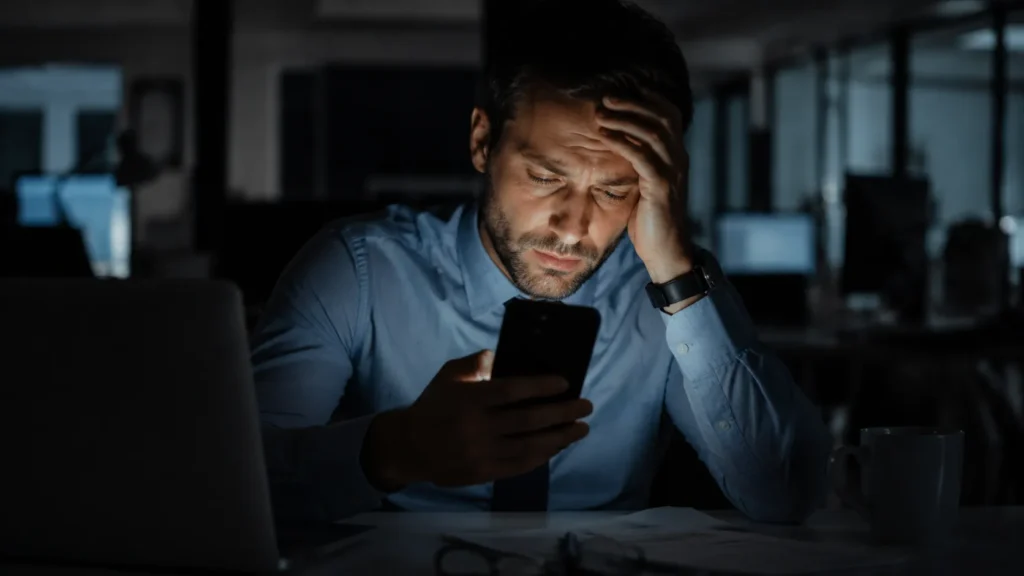 Profissional exausto olhando para o celular à noite